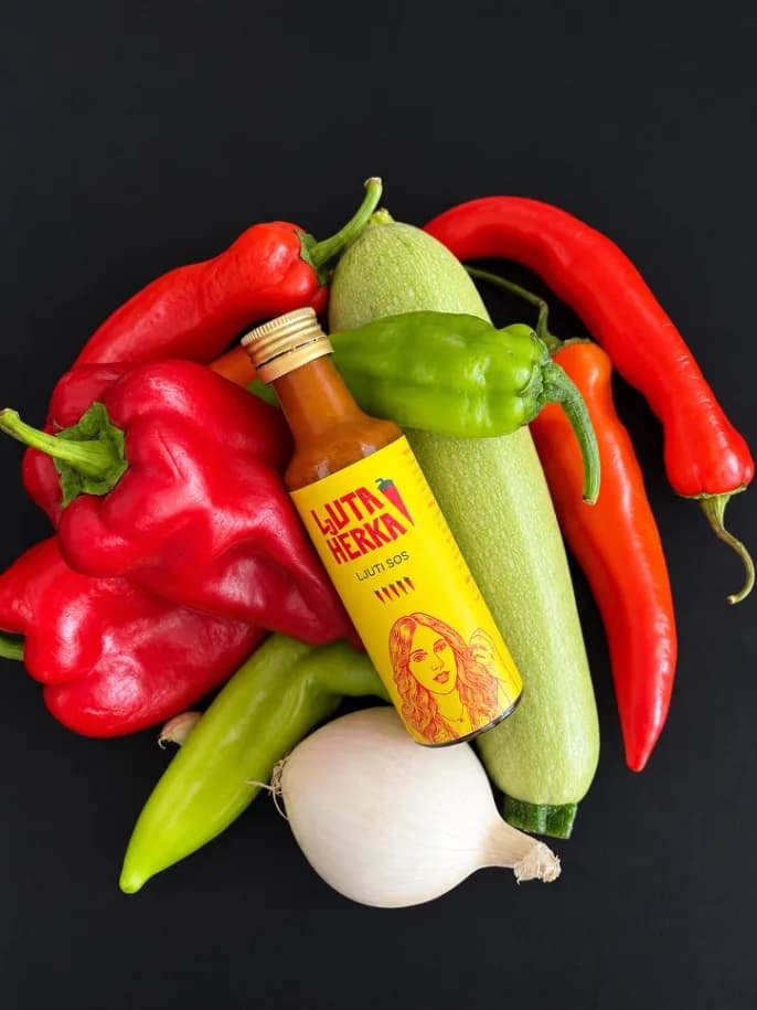 Bottle among peppers, zucchini and onion