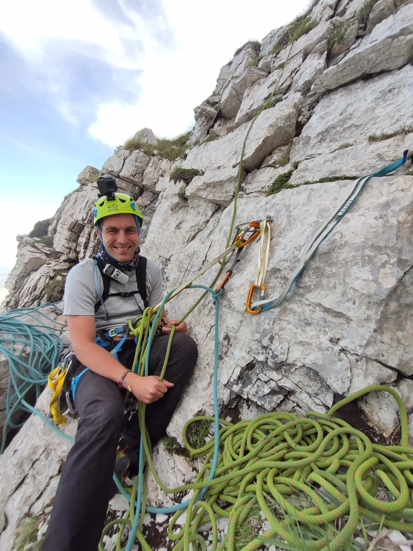 Dejan on a limestone climbing route, coiled ropes at his feet