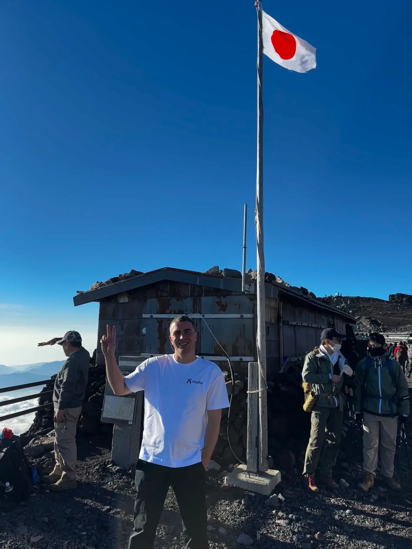 Dejan at the summit hut of Mount Fuji under a blue sky