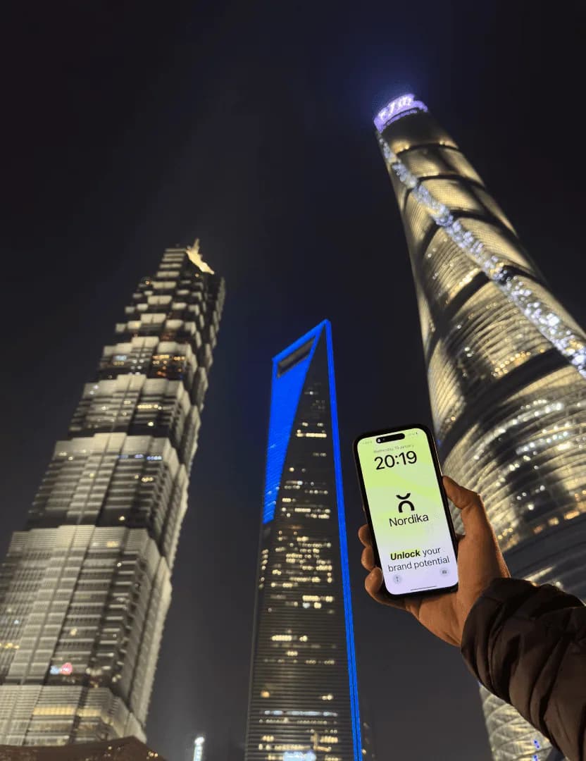 Nordika website on a phone in front of Shanghai towers